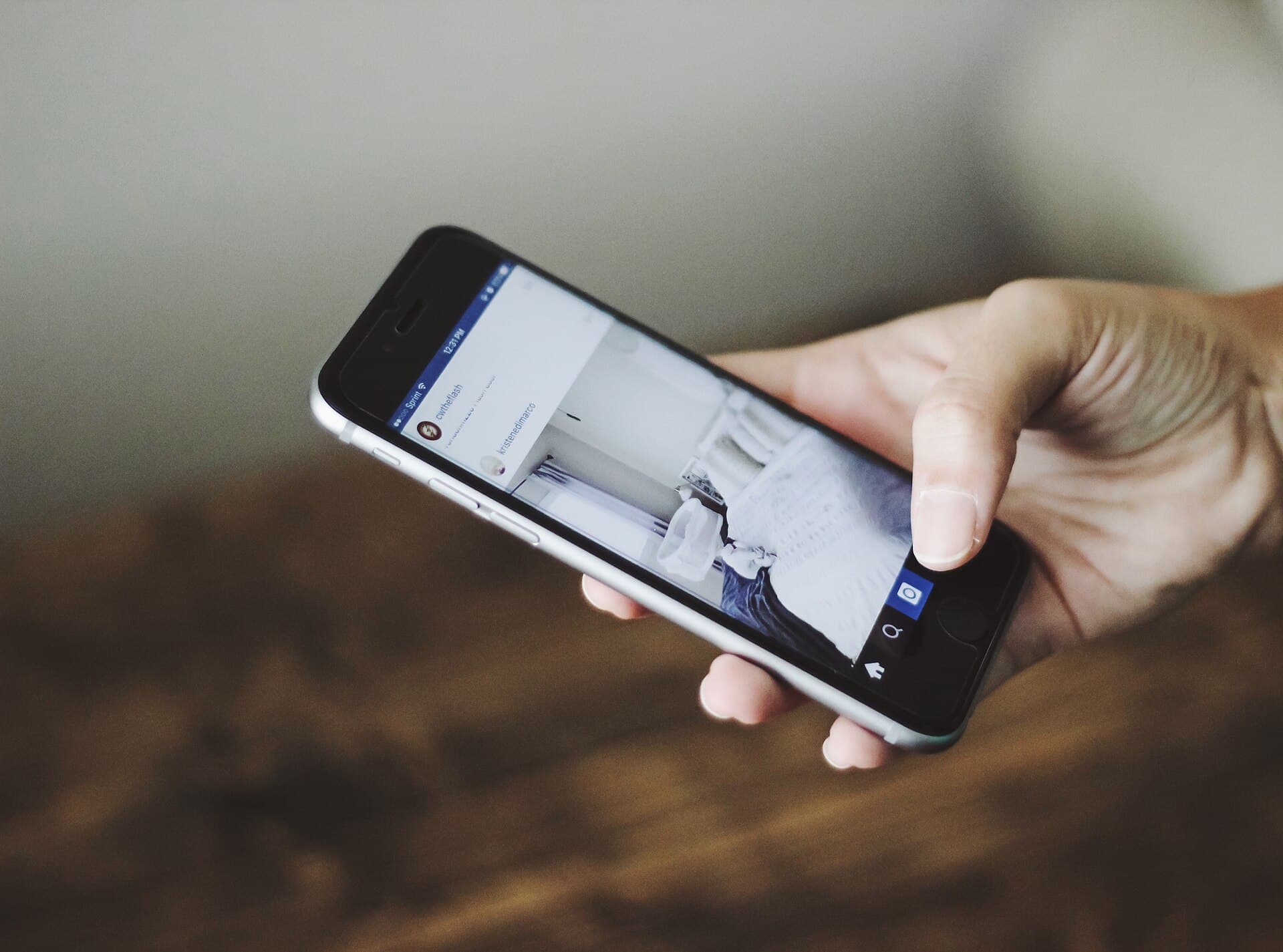 A hand holding a phone, scrolling through a social media feed