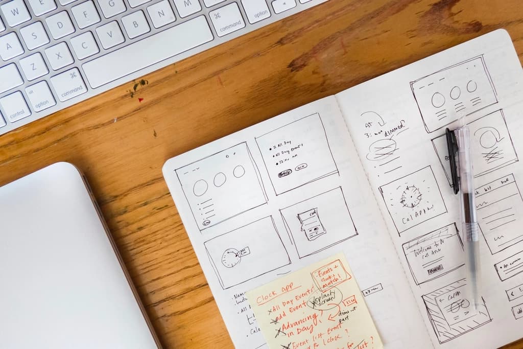Hand-drawn website page sketches on a notepad next to a keyboard